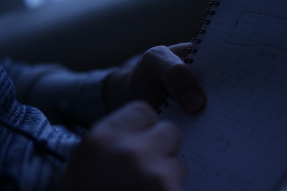 Hands writing in notebook, the making process