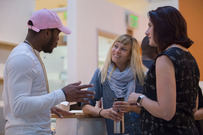 Three people in conversation, with one speaker gesturing while the others listen.