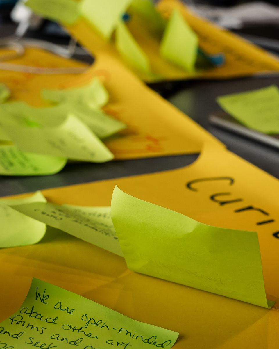 Close-up of handwritten sticky notes layered on sheets of yellow paper.